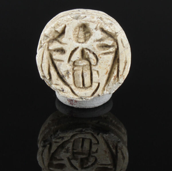 Egyptian button seal with protective uraei or Horus falcons flanking kheper beetle, holding rising sun